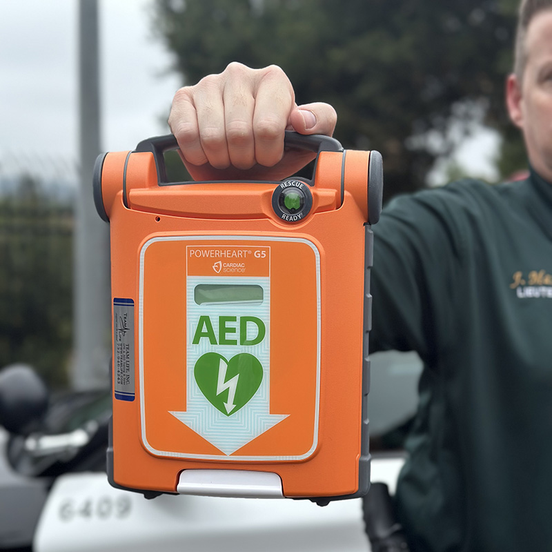 posse-aed_our-programs officer holding up an AED unit